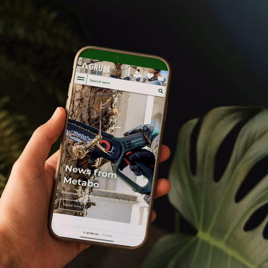 A hand holds a phone showing Grube's mobile shop, where a chainsaw cuts into a trunk under the headline News from Metabo.