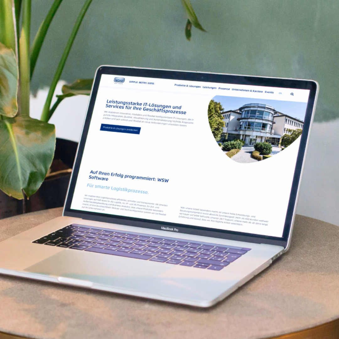 A laptop between two plants shows the WSW Software homepage and its promise of IT solutions and services for business processes.