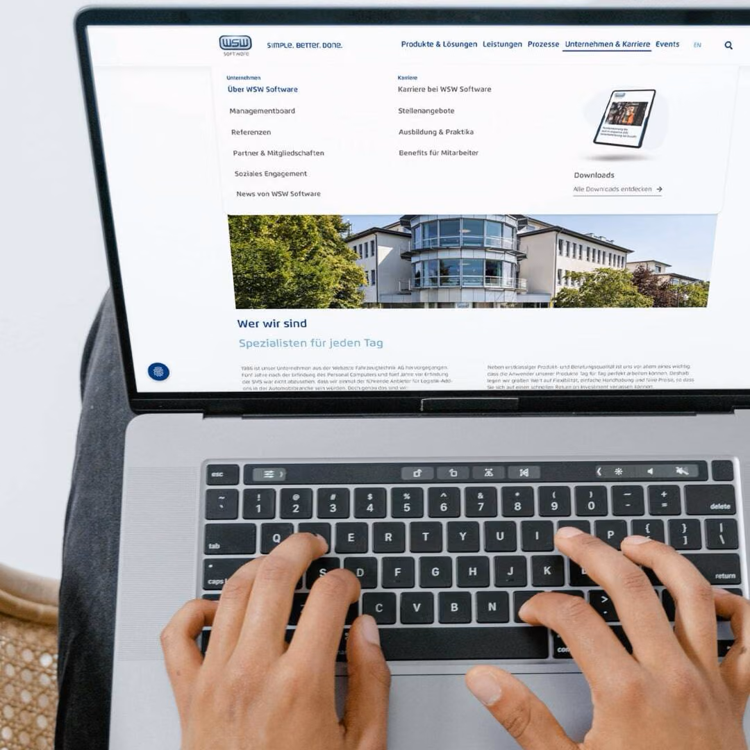 Hands type on a laptop showing the WSW Software site with its company and careers menu open.
