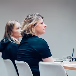 Two colleagues listening at a meeting table